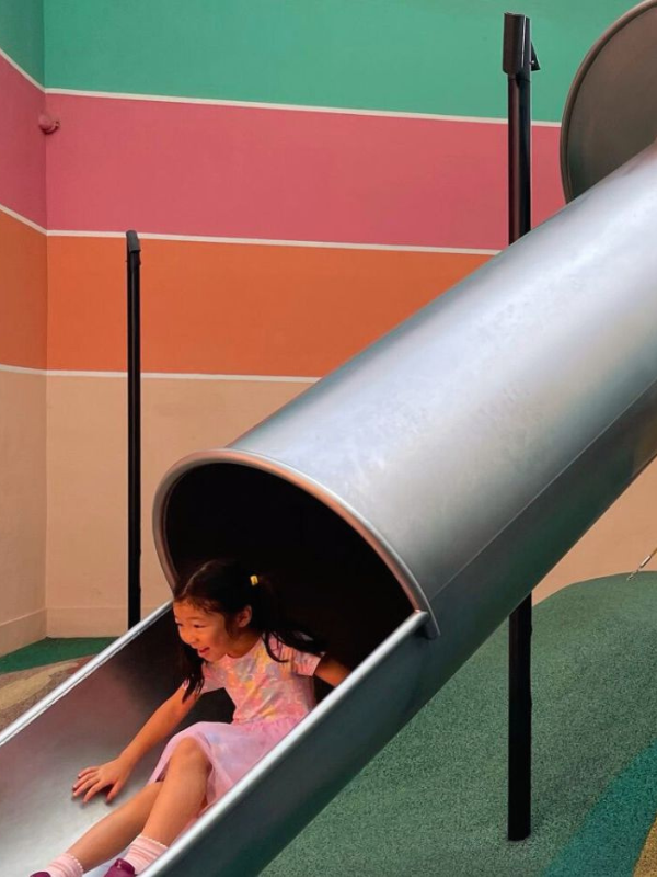 Little girl going down the slide at Great World Shopping Mall in Singapore Little Steps