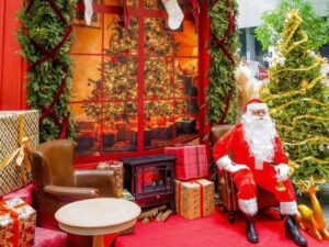 Image of Santa sitting by the Christmas tree - The Christmas Atelier 2026