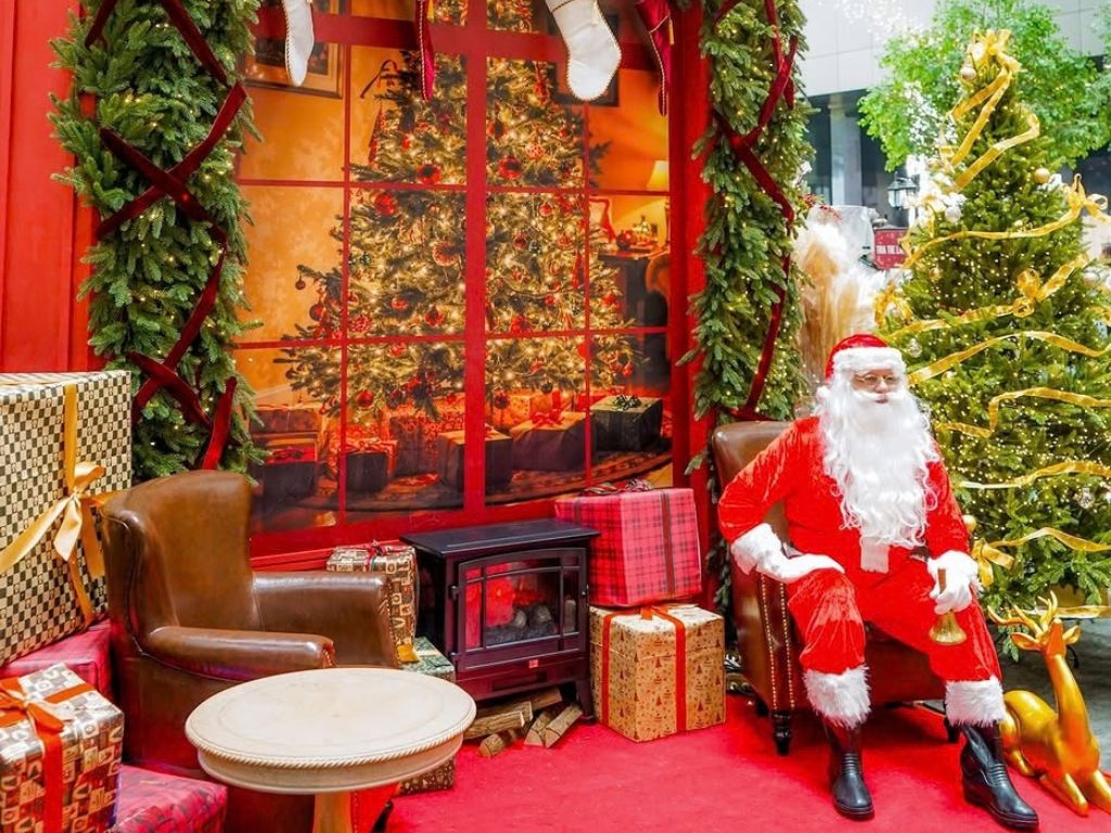 Image of Santa sitting by the Christmas tree - The Christmas Atelier 2026