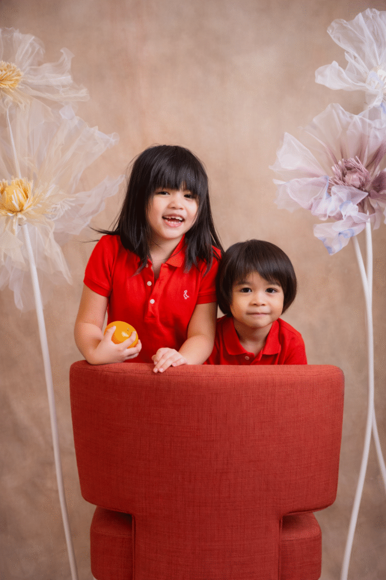 Two kids photographed together on a festive Chinese New Year set at Bambini Photography.