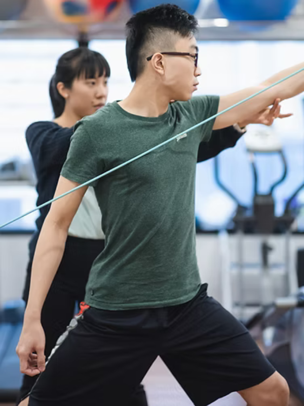 man in green t-shirt receiving strengthening muscle treatment
