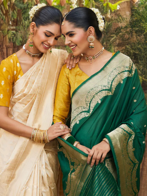 two indian women wearing saree's one in green with gold and the other in gold yellow and cream