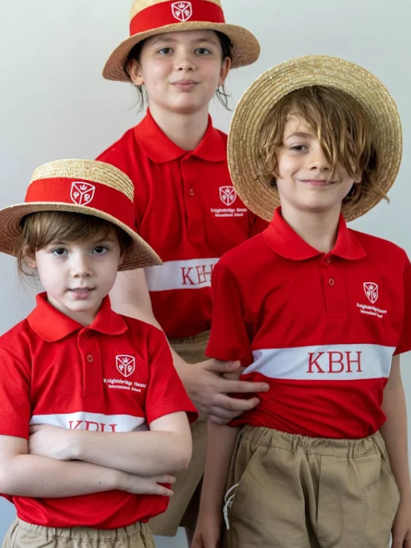 three students dressed in the red and white school uniform in Singapore