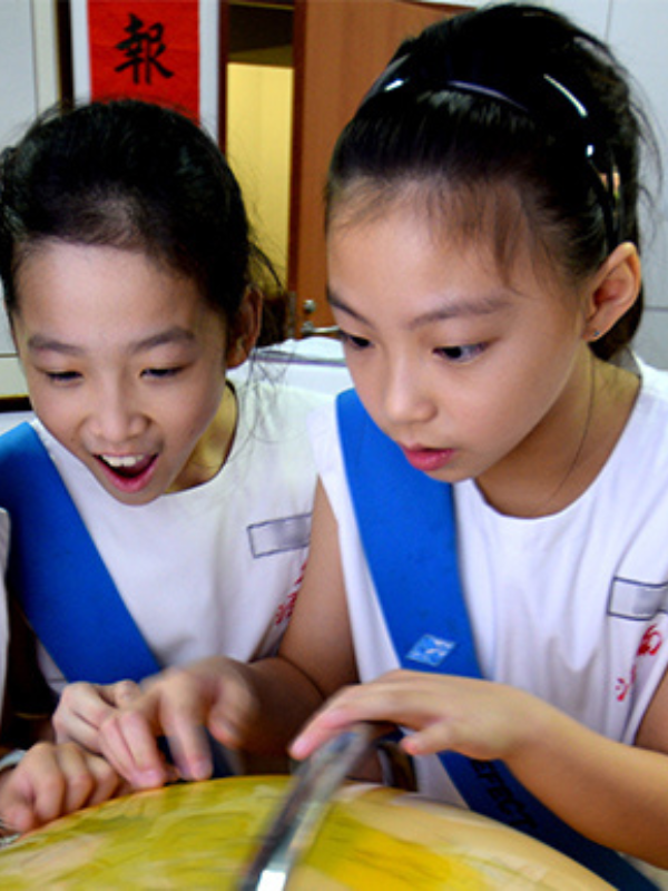 two students looking at a world globe