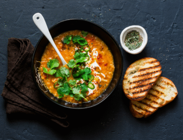 vegetarian chickpea curry with toasted bread and herbs on a black table