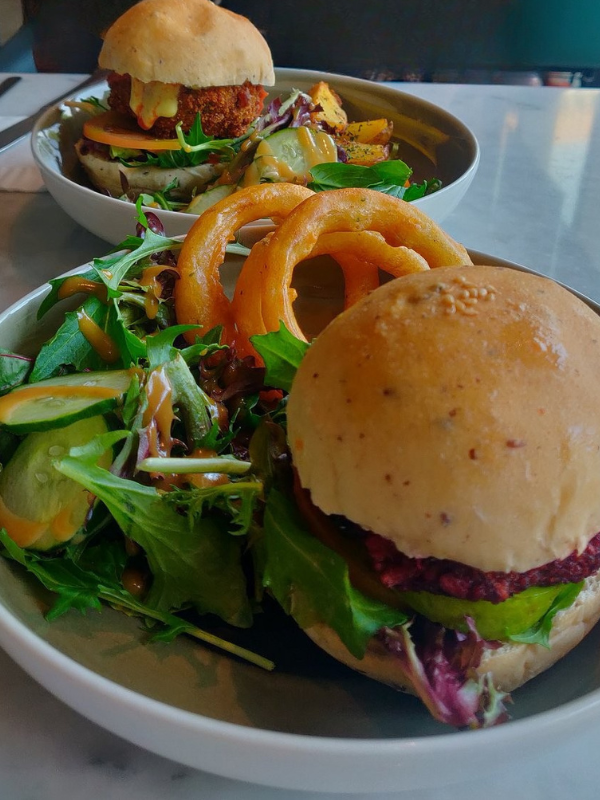 vegetarian burger with salad and onion rings sitting on a table