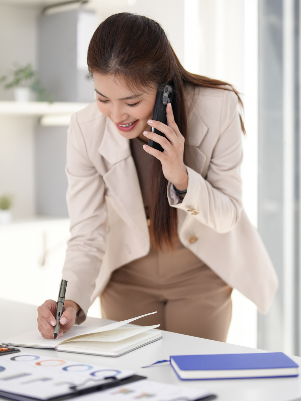 young asian business woman writing in an appointment book on the phone