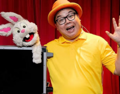 magician in yellow t-shirt with a rabbit puppet