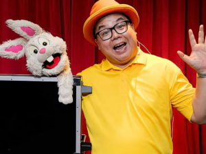 magician in yellow t-shirt with a rabbit puppet