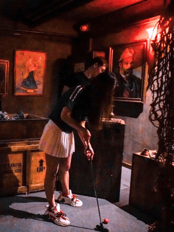 mystery mini golf room with old photos on the wall and a teen playing mini golf