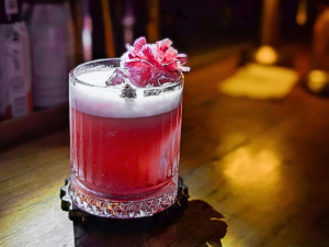 pink cocktail sitting on a wooden bar in Singapore Little Steps