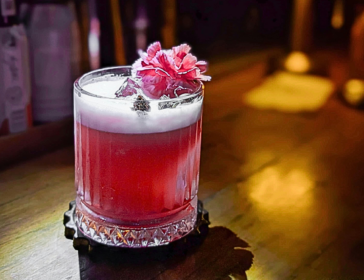 pink cocktail sitting on a wooden bar in Singapore Little Steps