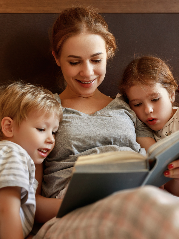 parent and children reading a book together before bed
