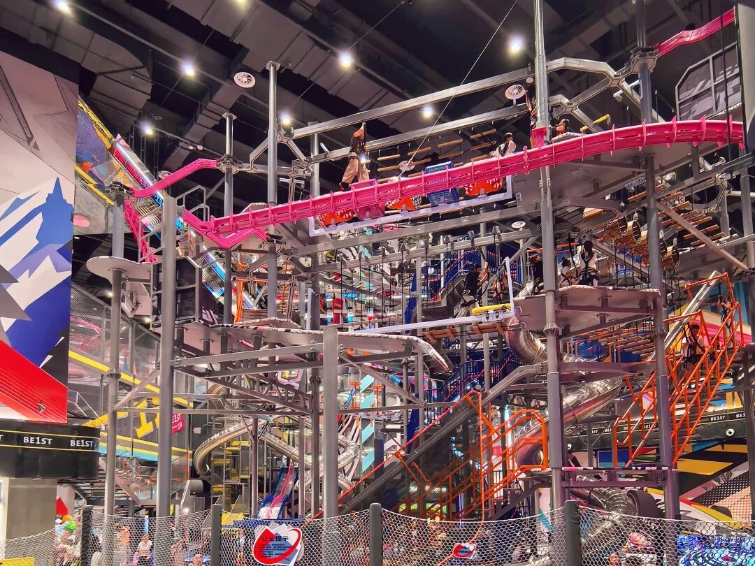 Multi-level ropes course with a pink Rail Fly track and silver slides at BE1ST indoor adventure park in Pudong, Shanghai