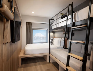 Family loft room at Moxy Niseko Village with a queen bed, bunk bed ladder and snowy Mt Yotei framed in the window