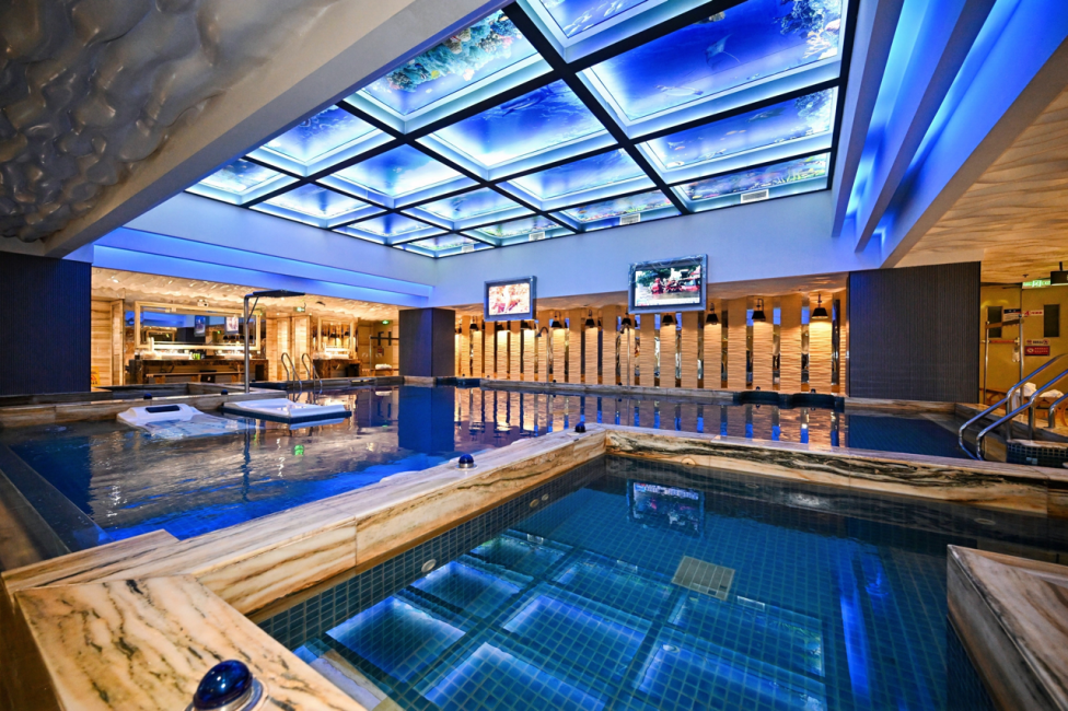 Heated indoor hot spring pool under a glowing blue glass ceiling at Aqila Hot Spring in Nanshan, Shenzhen