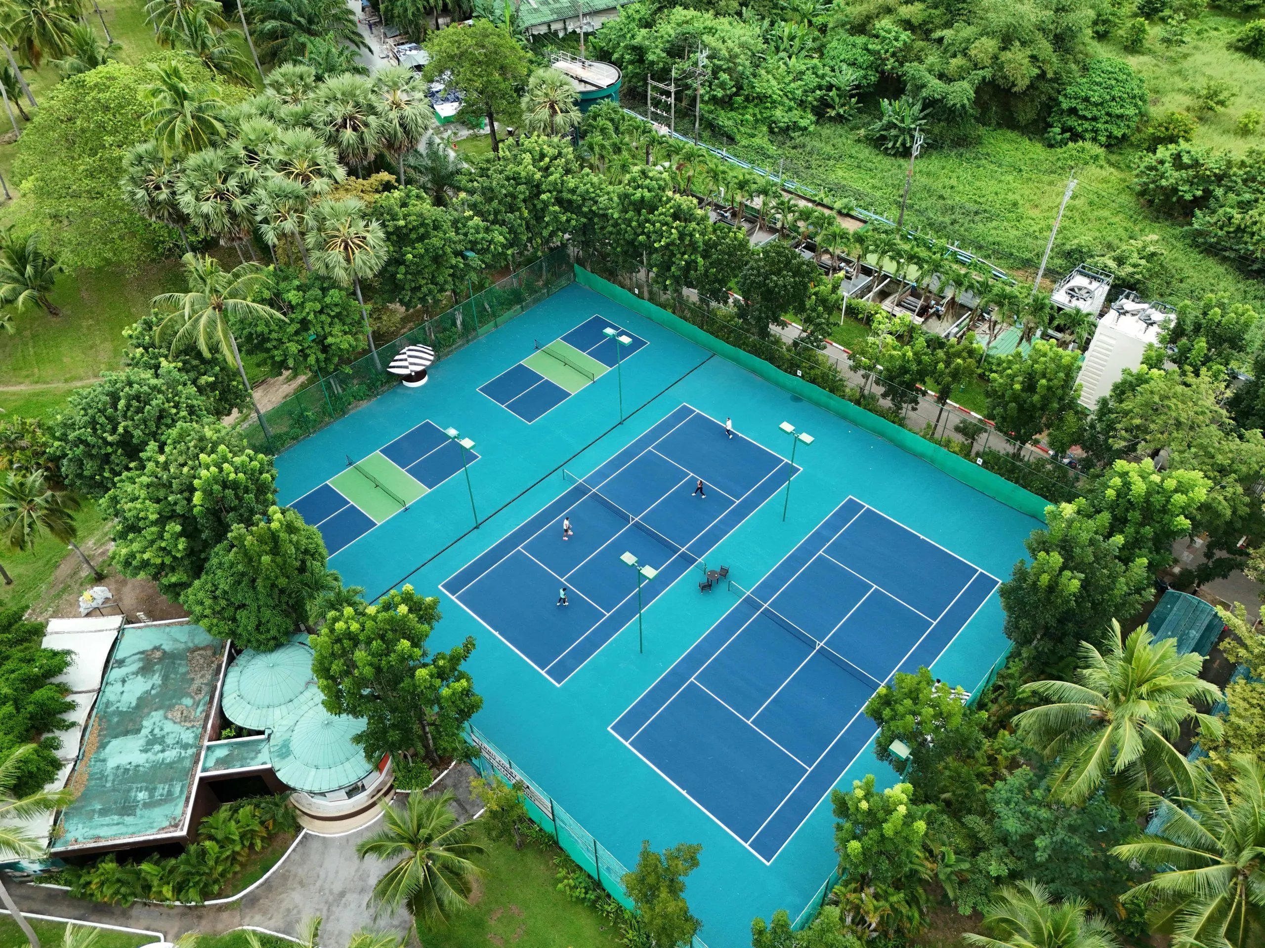 Aerial view of the pickleball and tennis courts among palm trees at Pullman Phuket Karon Beach Resort