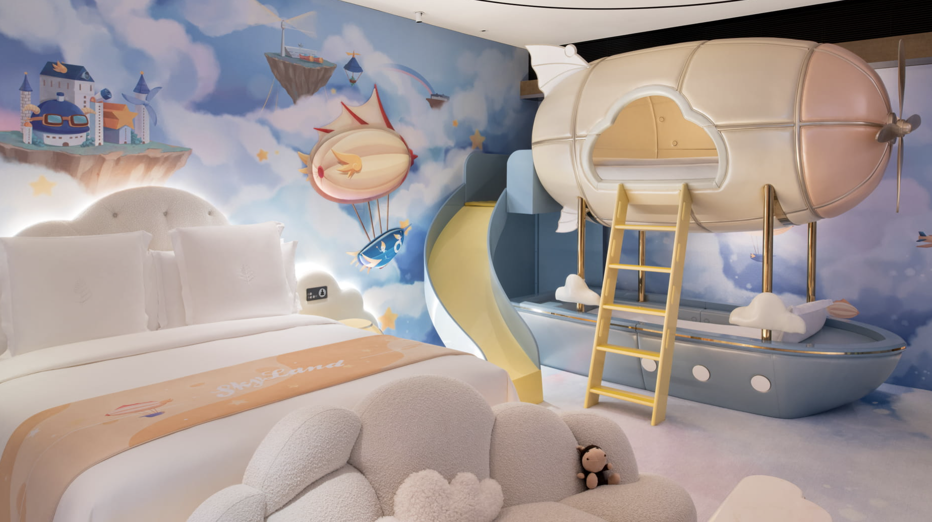 Sky-themed kids room with airship bunk, slide and cloud sofa beside a king bed at Four Seasons Hotel Guangzhou